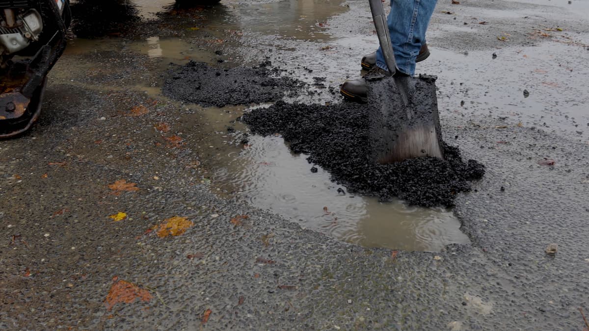 Shovel pouring EZ Street into a water-filled pothole